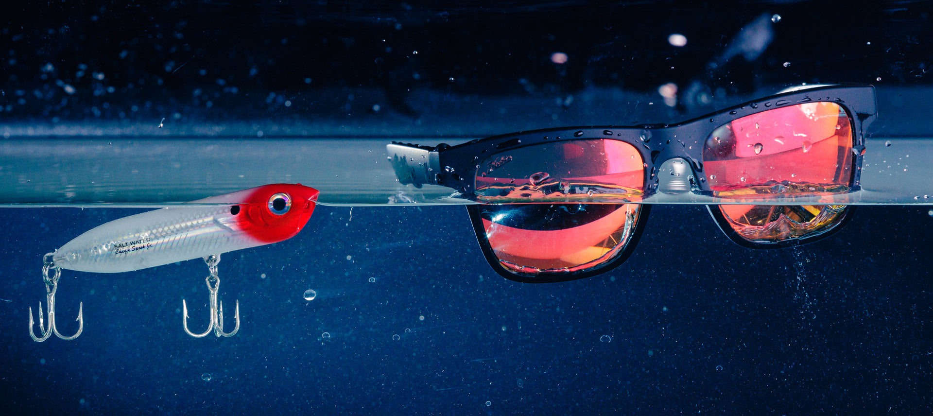 Hobie Eyewear Coastal Polarized Sunglasses floating next to a fishing lure.